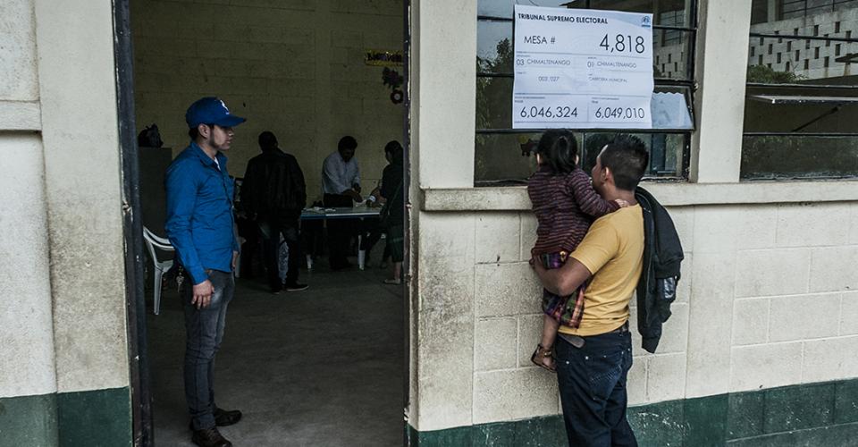 Una niña observa curiosa el momento en que su madre deposita el voto en un centro de votación de Chimaltenango.