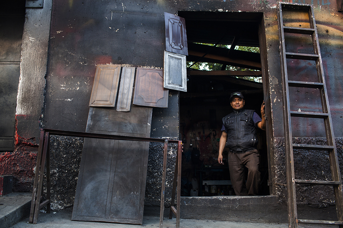 Rigoberto Sinaj en la puerta de su tienda de herrería, bajo el paso a desnivel.