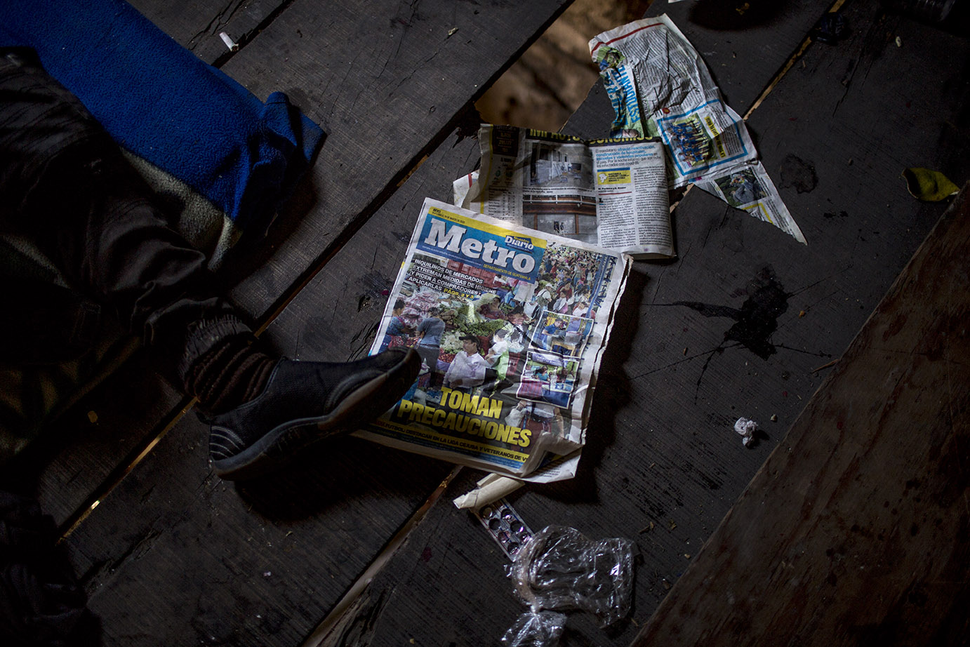 Un vagabundo descansa en el piso de una casa abandonada donde luce el detalle de la portada de un periódico de reciente publicación. Simone Dalmasso