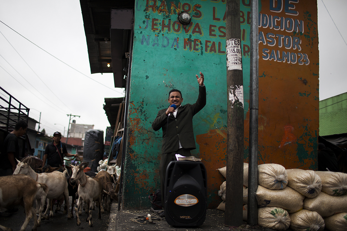 Un pastor evangélico lleva a cabo su sermón entre costales de maíz y cabras
