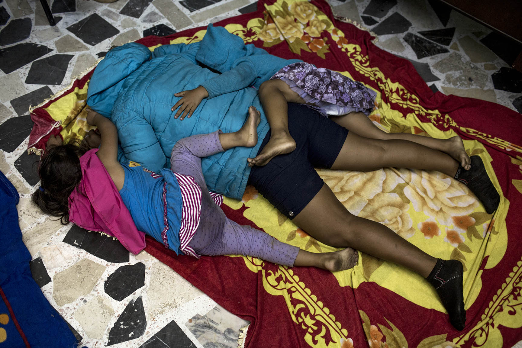 Karen y Seidy Díaz duermen tiradas encima de su mamá, Silvia, al suelo, recién llegadas al albergue de Puebla / Simone Dalmasso