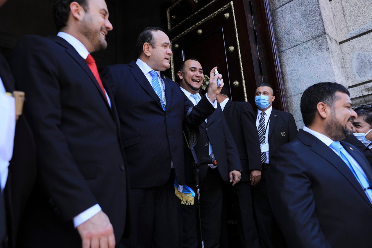 Alejandro Giammattei bromea con unos diputados enseñando spray antibacterial a la prensa mientras sale del Congreso, después de la sesión, el 19 de marzo.